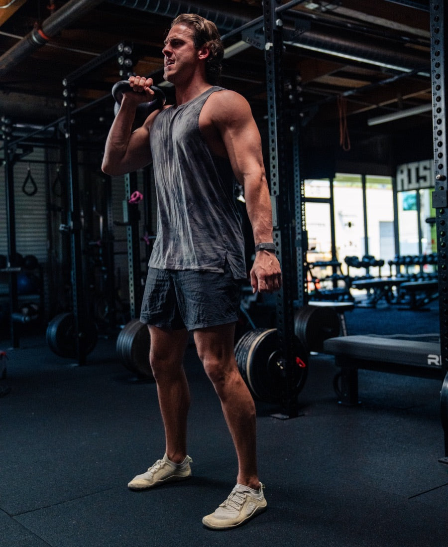 A man mid-set in a gym, holding a kettlebell in the front rack position