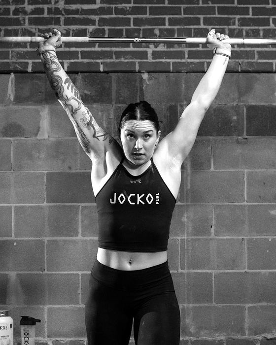 Mattie Rogers pressing a barbell overhead in a Jocko Fuel tank