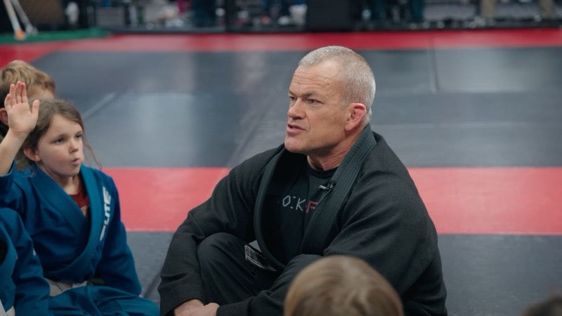 Jocko Willink talking with a group of kids on the mats